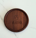 Wooden coaster with 'ìtùnu' branding on a marble surface.