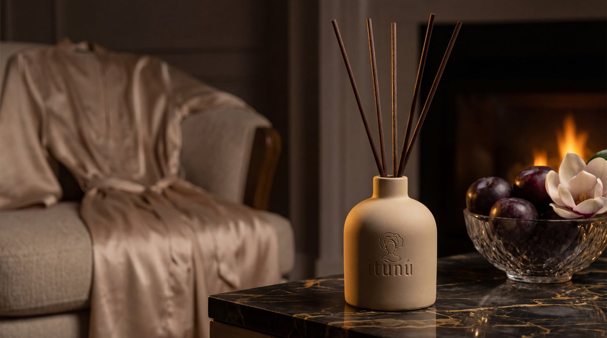 Cream Ceramic diffuser with reeds on a table in front of a fireplace
