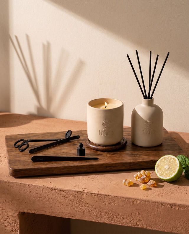 The Ìtùrá Complete Set on its walnut tray, the candle, diffuser and black tools on a terracotta bench against a wheat wall, with bergamot and amber resin