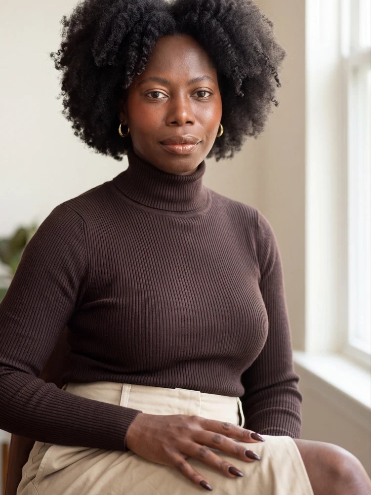 Victoria Songonuga, LCPC, seated by a window in a brown turtleneck